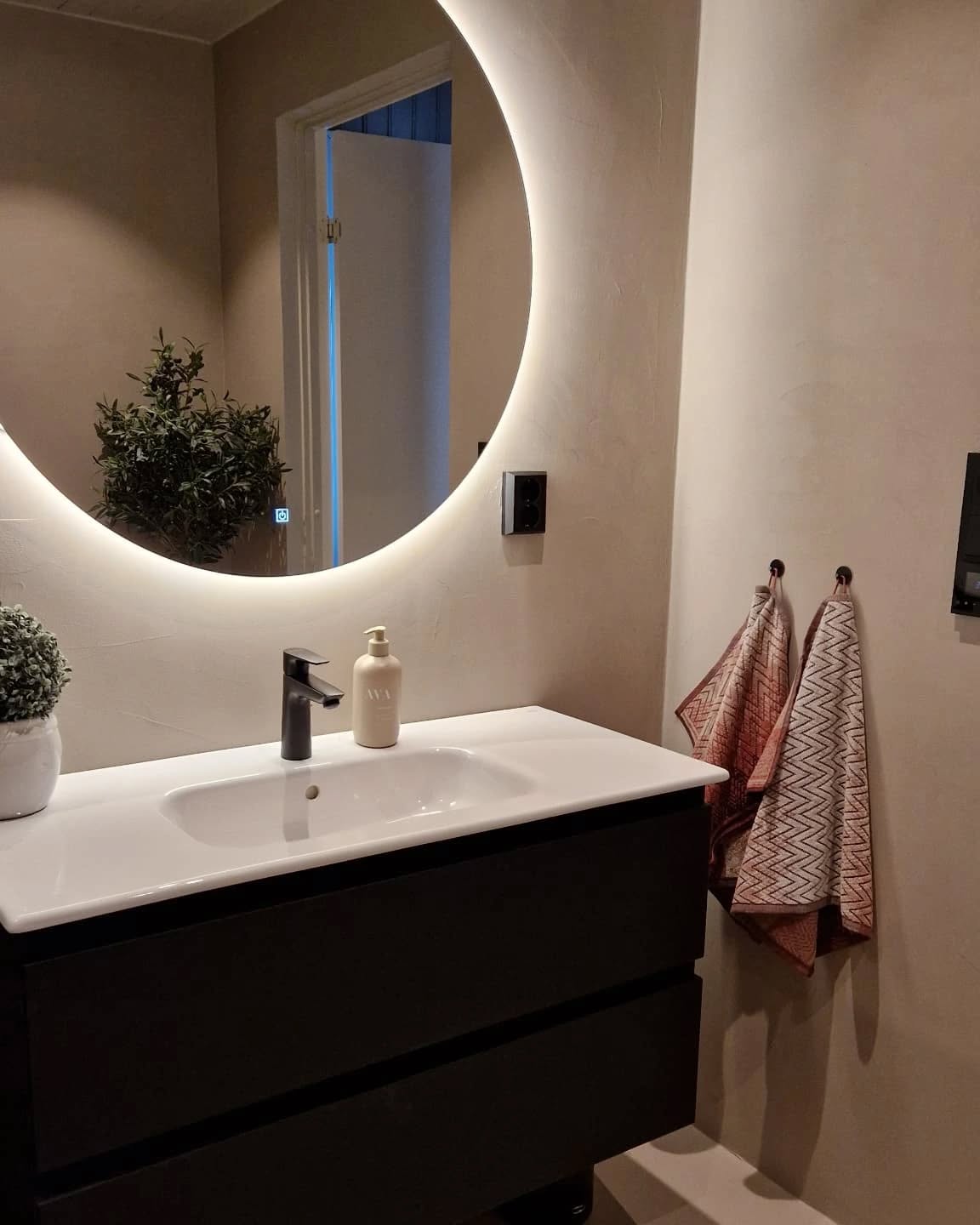 Baderom med opplyst speil og moderne vask